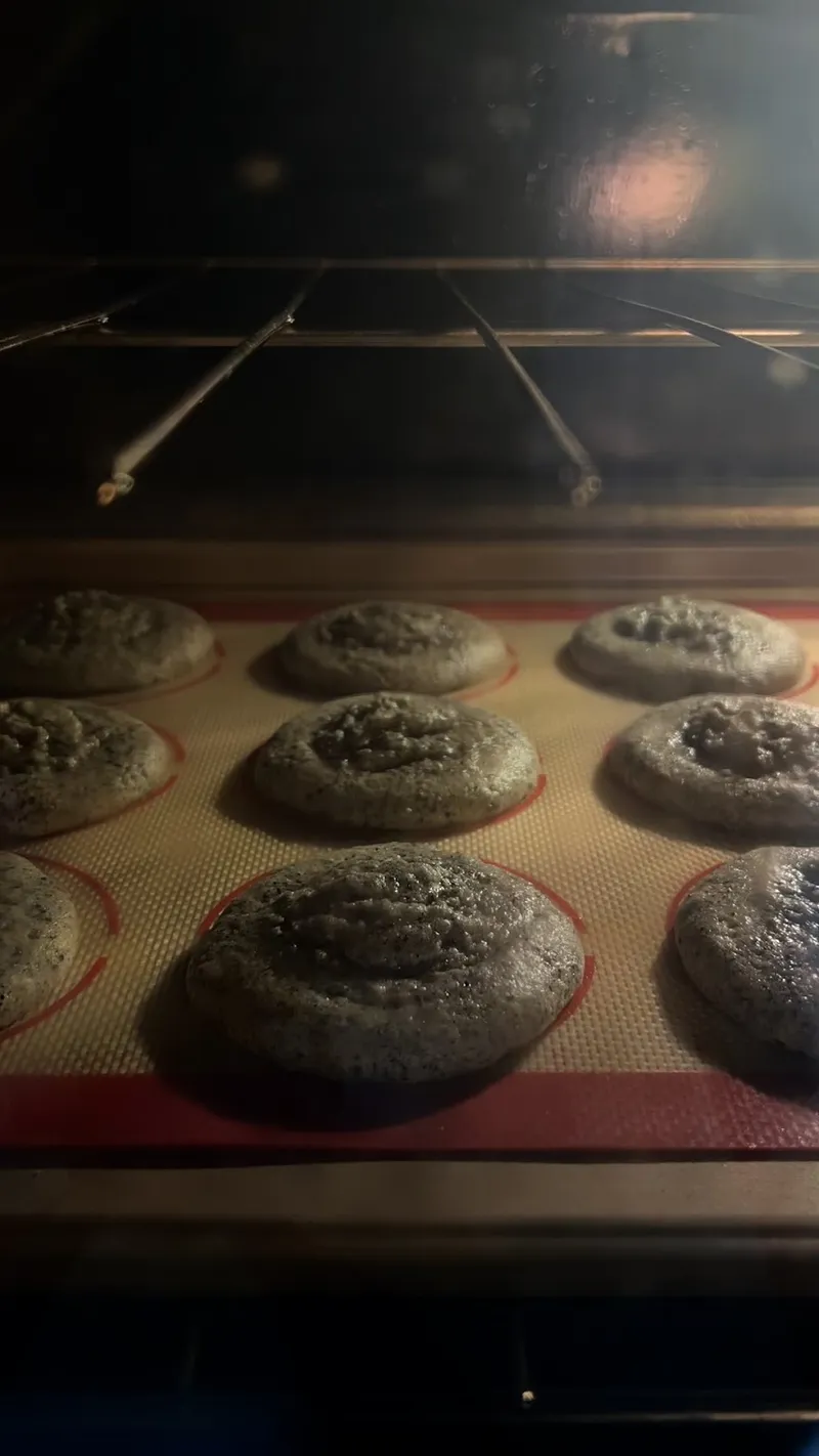 Soft and chewy black sesame cookies baking in the oven on a silicone mat