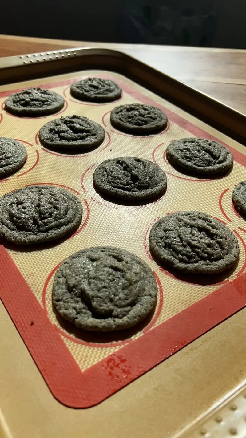 Freshly baked black sesame cookies cooling on the baking sheet