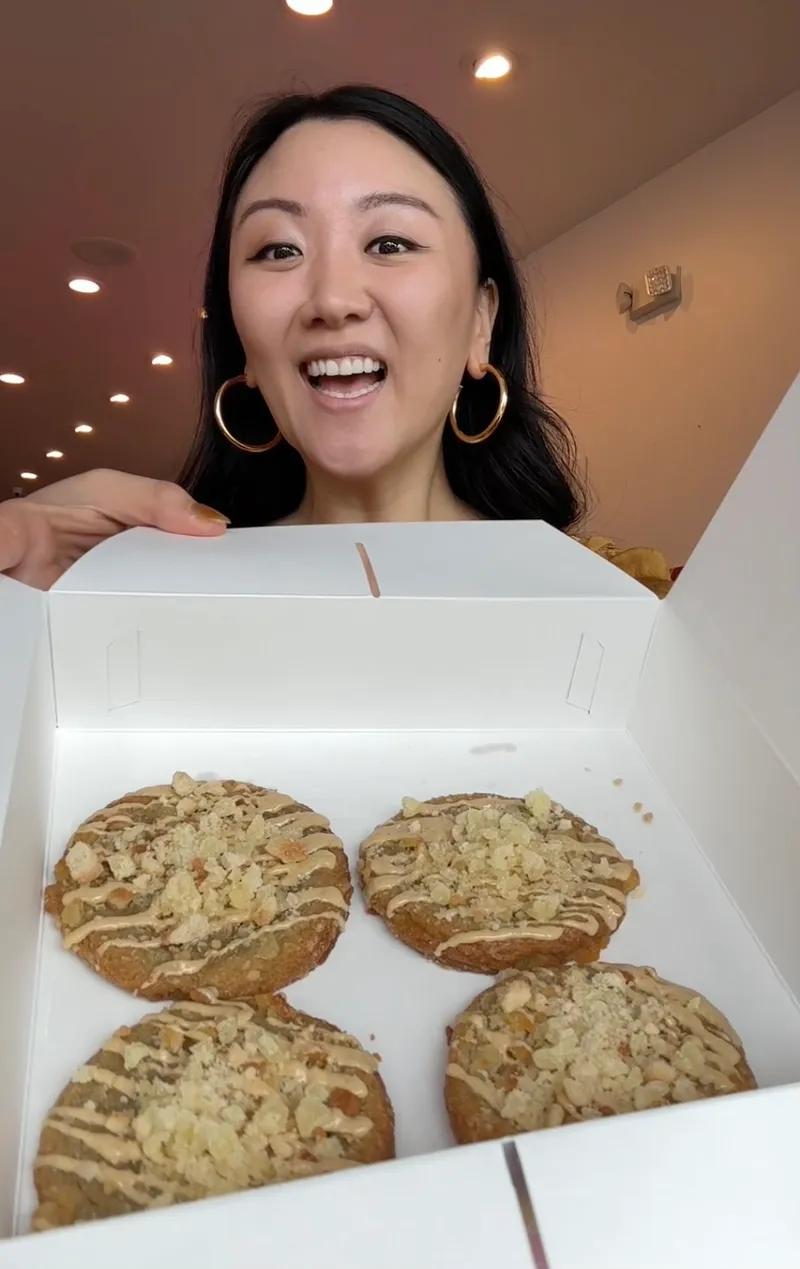 Jasmine holding a box of custom pineapple cake cookies at Dough & Arrow