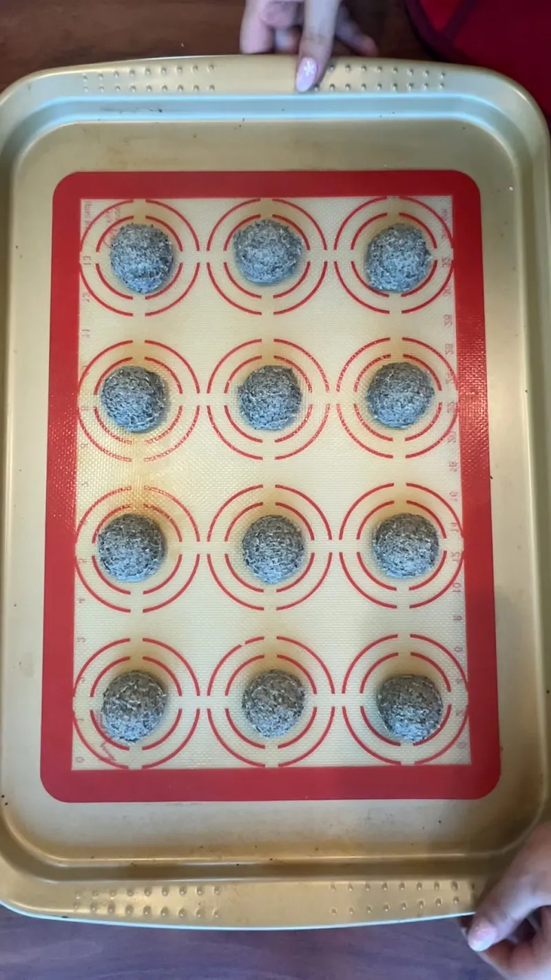 Black sesame cookie dough scooped into balls on a silicone baking mat