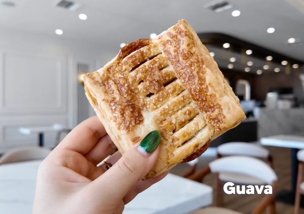 Hand holding the 85°C Bakery guava cheese strudel pastry with flaky golden layers