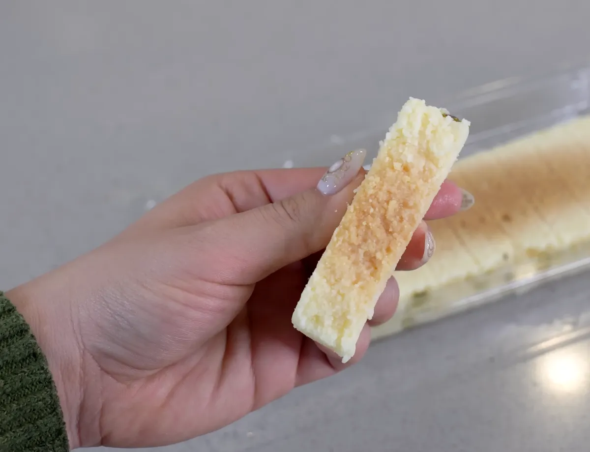 Jasmine holding a single slice of Nanak milk cake kalakand showing its crumbly golden-topped texture