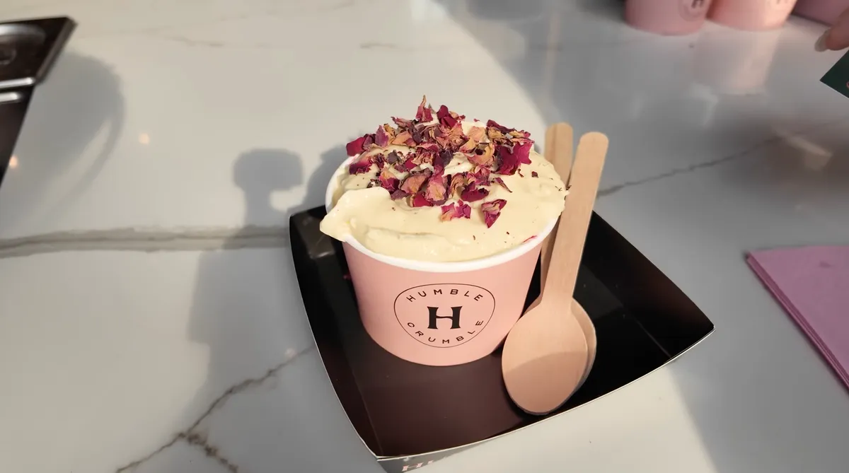 Humble Crumble custard dessert topped with dried rose petals in a pink branded cup