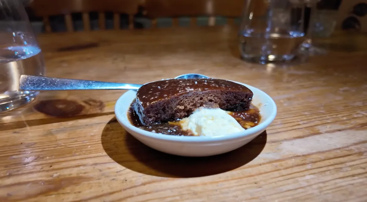 Sticky toffee pudding with clotted cream in a white bowl at The Mug House, Borough Market