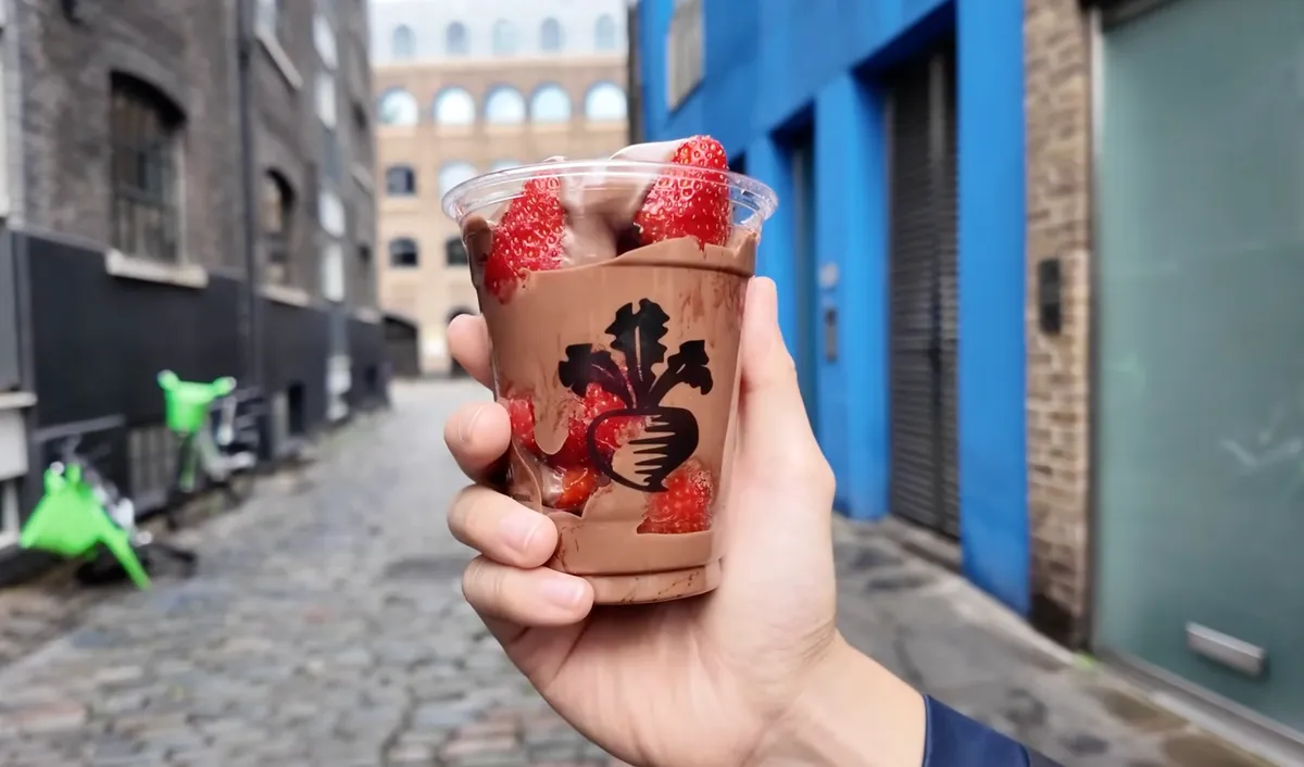 Turnips chocolate covered strawberries held up in a Borough Market alleyway