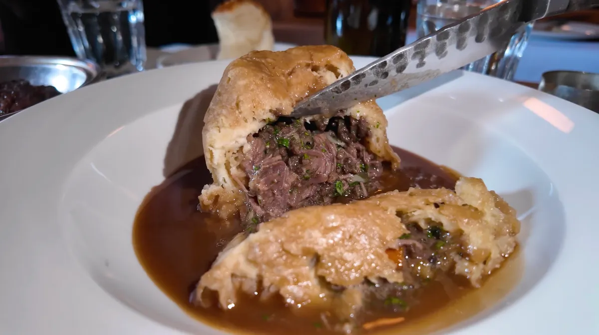 The Devonshire beef cheek and Guinness suet pudding cut open in dark gravy