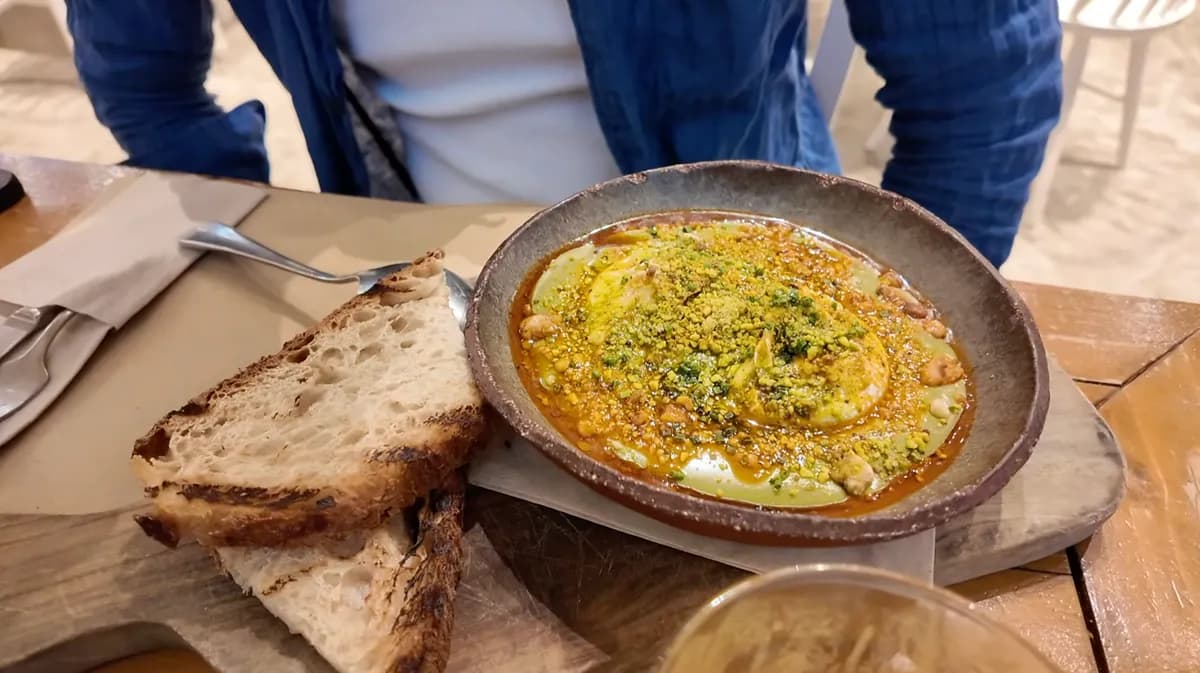 Shakshuka with pistachio topping in a stone bowl served with toasted bread at ERGON House Athens
