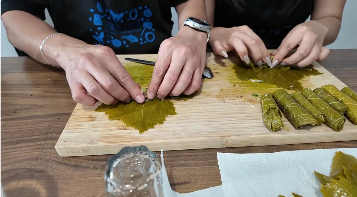 Jasmine and George rolling dolmades in grape leaves during their Athens Greek cooking class