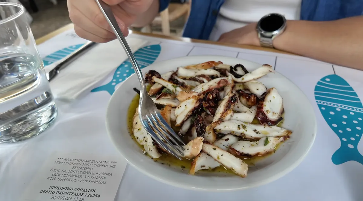 Grilled octopus in olive oil on a white plate at a seafood restaurant in Athens