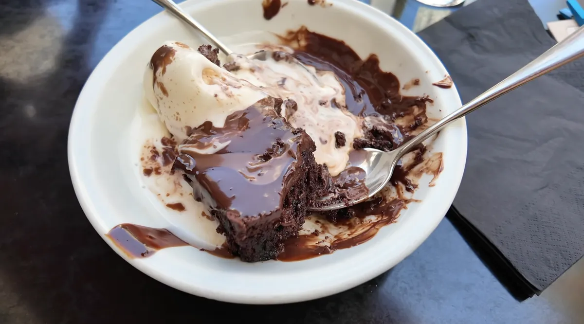 Dense chocolate cake with melted chocolate sauce and a scoop of vanilla ice cream at Nancy's Sweet Home Athens