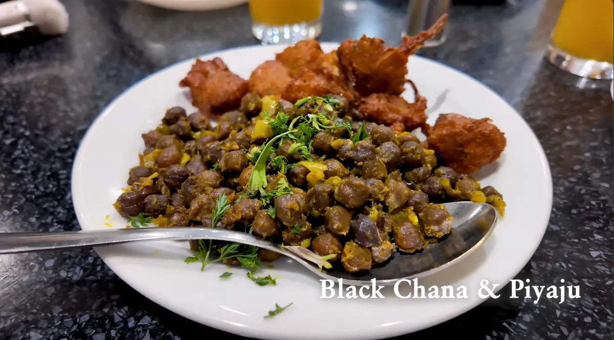 Black chana and piyaju (fried onion fritters) on a white plate at Cafe Grill, Brick Lane