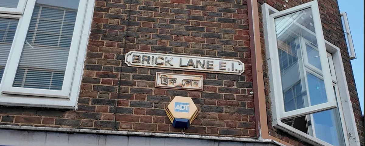 Brick Lane E1 street sign on a brick wall with Bengali script below