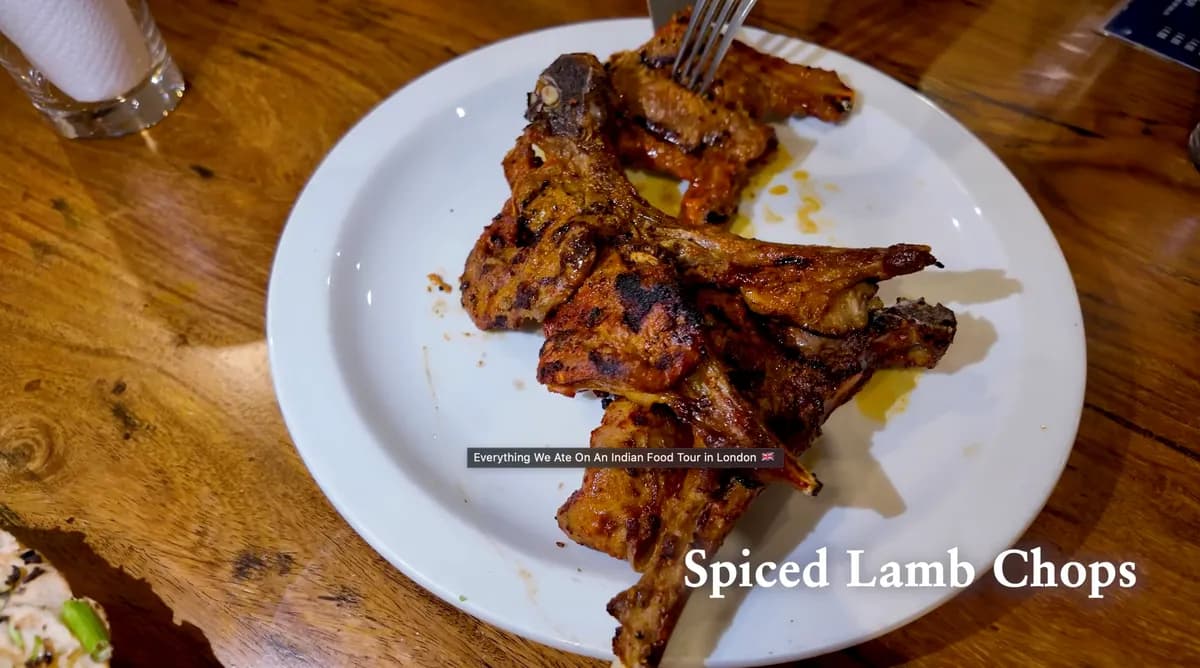 Spiced lamb chops on a white plate at Lahore Kebab Shop, charred and marinated