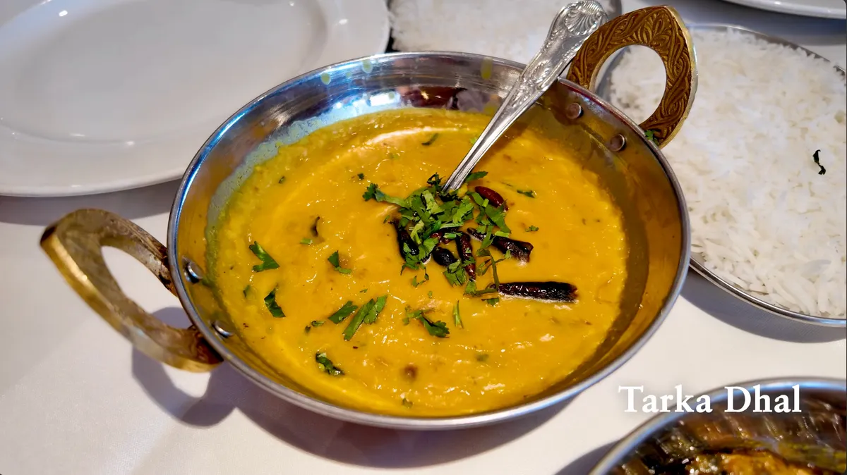 Tarka dhal in a brass-handled karahi with dried chili and cilantro garnish at Eastern Eye